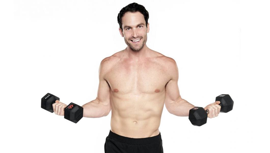 Barry's instructor Alex Sapot in shirtless posing with dumbbells