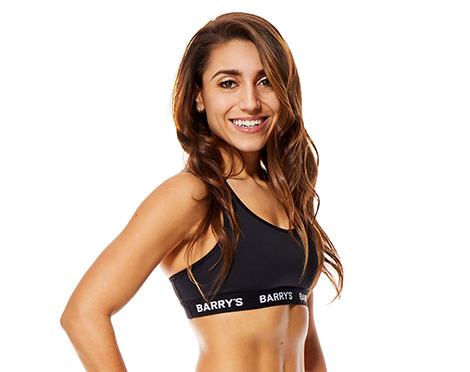 Headshot of instructor Amanda Asaro in black Barry's Bootcamp sports bra with hand on hip smiling on white background