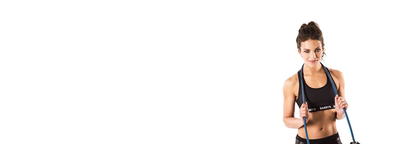 Barrys instruktör Anya Lahiri i svart sport-bh poserar med hopplina