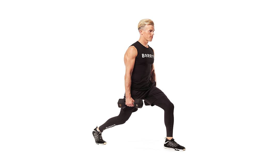 Barry's Bootcamp instructor Brendan Sorichetti standing against a white background doing a lunge with dumbbells in hand.
