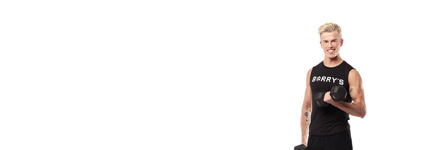 Barry's Bootcamp instructor Brendan Sorichetti standing against a white background doing a bicep curl with one arm.