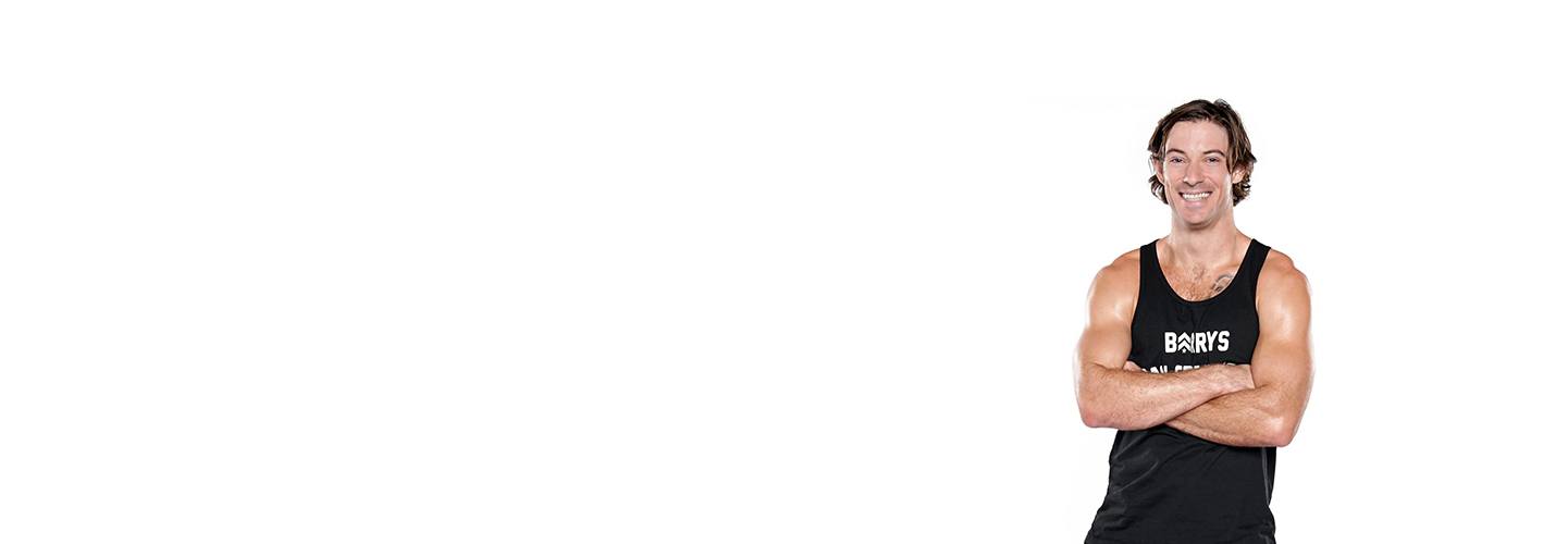 El instructor de Barry, Brian Tschida, con una camiseta sin mangas negra, posa con los brazos cruzados.