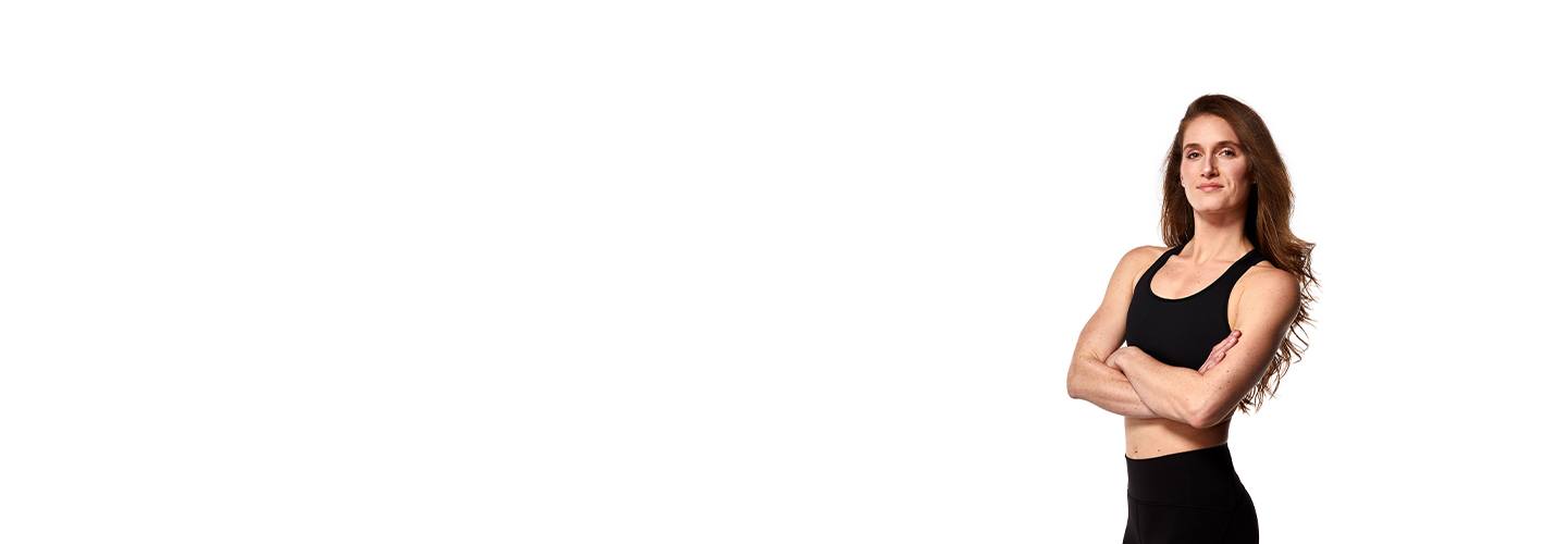 Instructor Candice Peak in black sports bra with arms folded over chest on white background