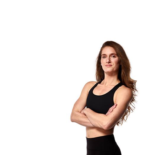 Instructor Candice Peak in black sports bra with arms folded over chest on white background