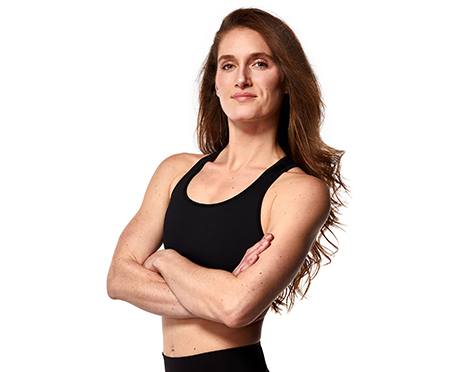 Headshot of instructor Candice Peak in black sports bra with arms folded over chest on white background