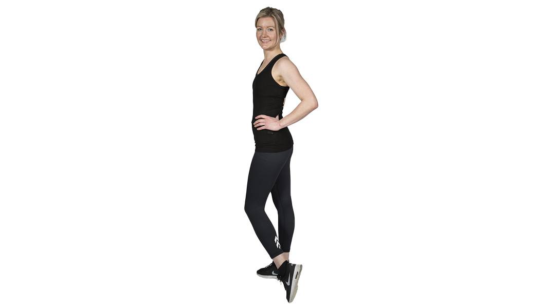 Barry's Bootcamp instructor Cecilie Sletteng in black tank top smiling with hand on hip on white background