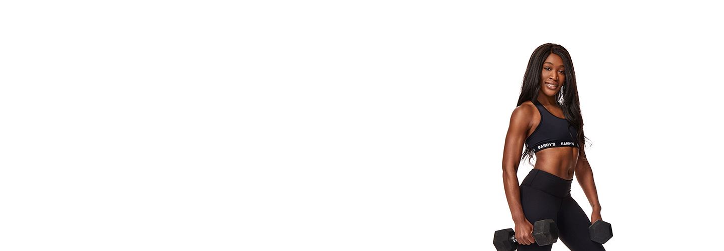 Barry’s instructor wearing a black top standing confidently smiling against a white background