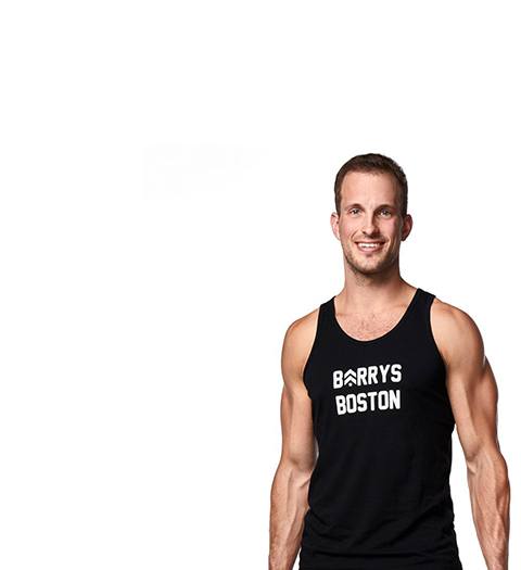 Instructor Greg Ux in black Barry's tank holding dumbbells at their side