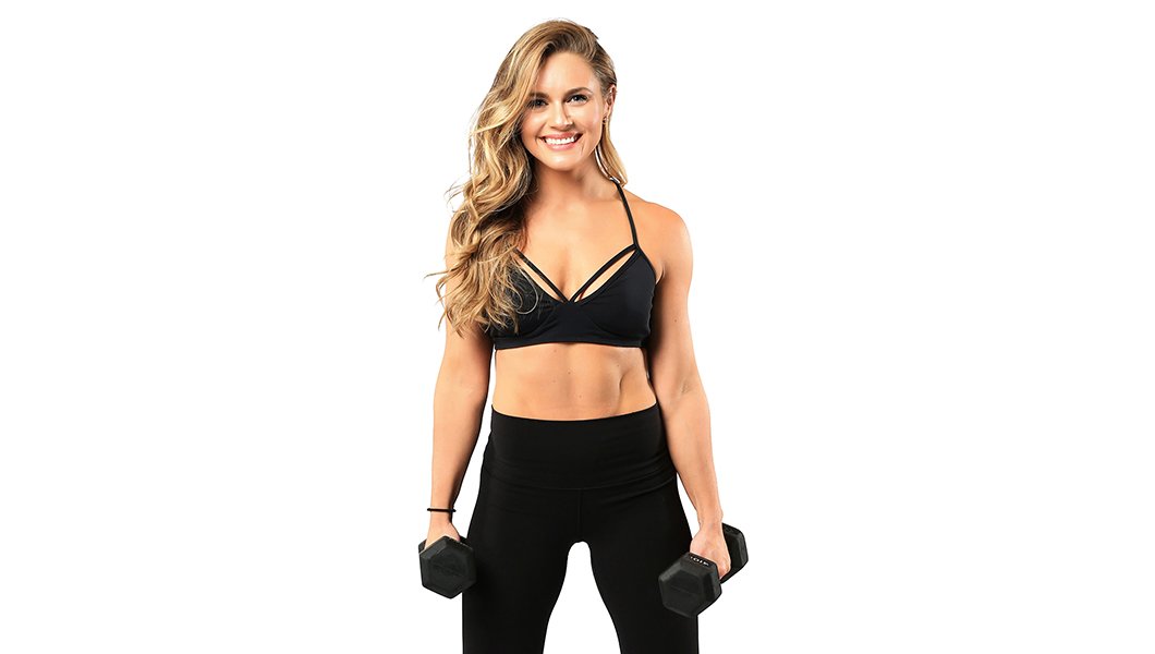 Instructor Holly Keskey-Koester in black sports bra smiling and holding dumbbells on white background