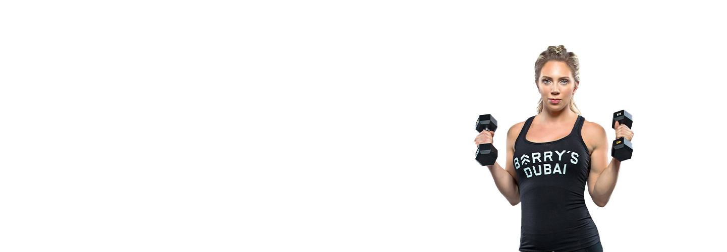 Instruktör Jade Blackmore i svart Barry's Bootcamp linne som håller hantlar på vit bakgrund