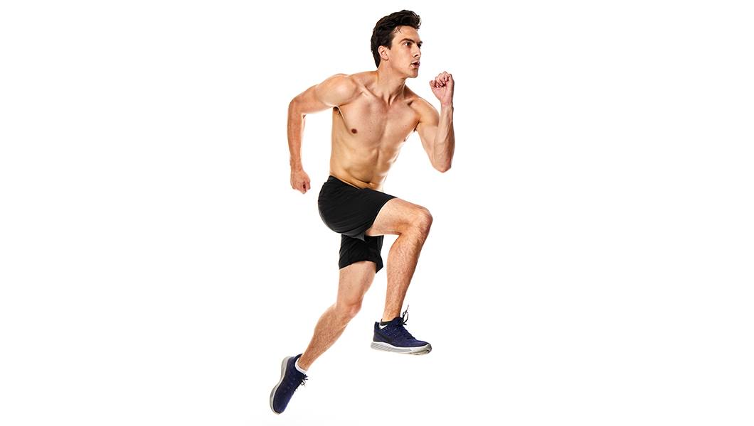 Shirtless Barry's Bootcamp instructor Jimmy Nicholas starting sprint exercise on white background