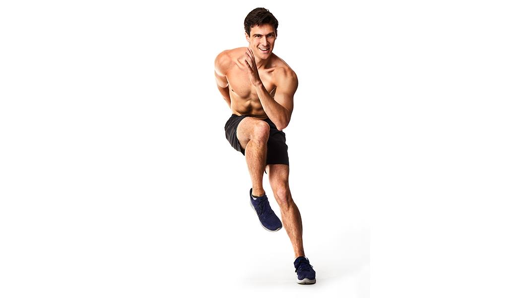 Shirtless Barry's Bootcamp instructor Jimmy Nicholas doing side skier exercise on white background