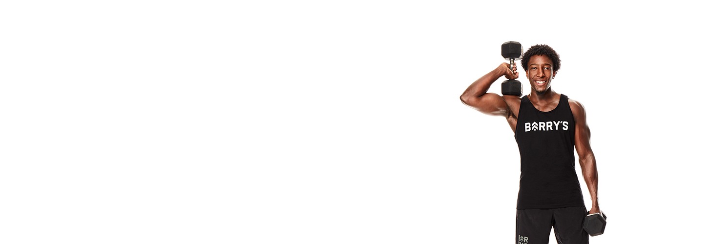 Barry's Bootcamp instructor Joseph Allen wearing a black tank top with a Barry's logo on it holding a dumbbell up near his shoulder.