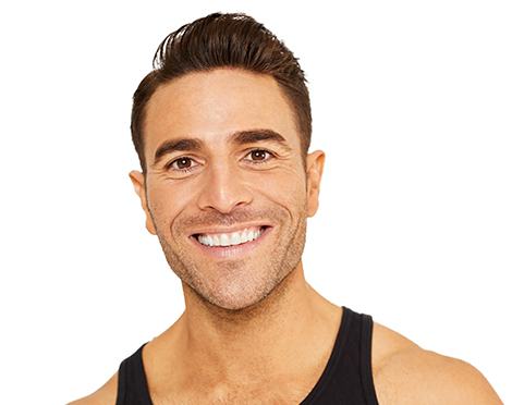 Barry’s instructor wearing a black top standing confidently smiling against a white background