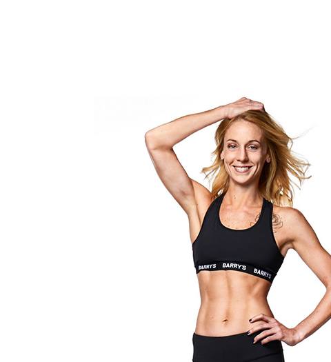 Barry's Bootcamp instructor Kelly Whittaker in black Barry's Sports bar. One hand on head and the other on hip.