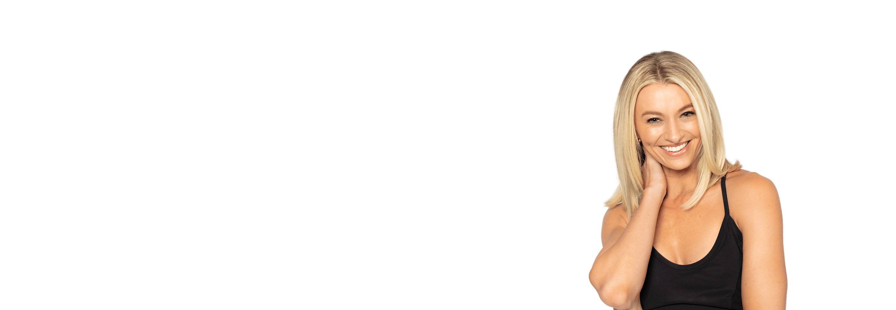 Barry’s instructor wearing a black top standing confidently smiling against a white background