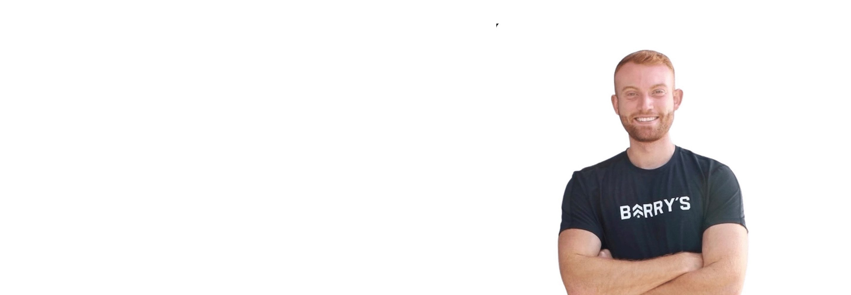 Barry’s instructor wearing a black top standing confidently smiling against a white background