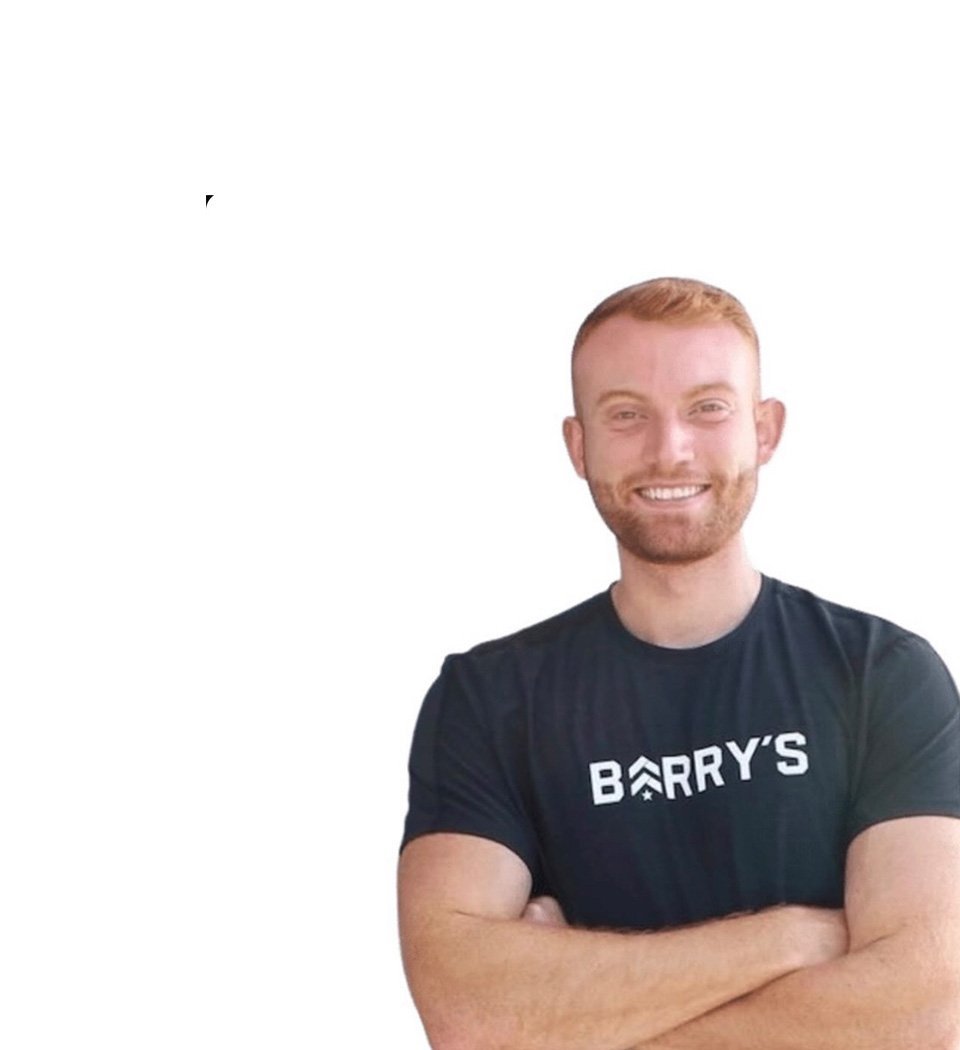 Barry’s instructor wearing a black top standing confidently smiling against a white background