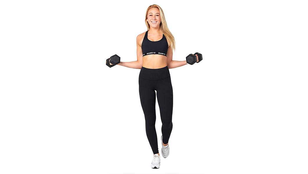 Headshot of Barry's Bootcamp instructor Madeline Consoer holding two dumbbells out at her sides, wearing a black sports bra against a white background.