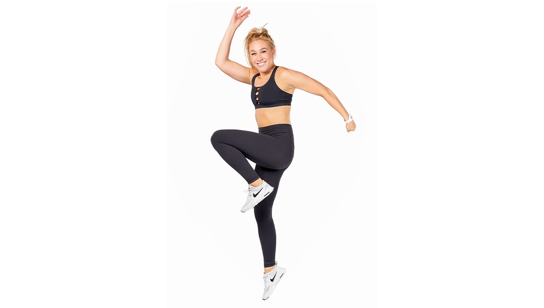 Barry's Bootcamp instructor Madeline Consoer doing a high-knee exercise move, wearing a black sports bra against a white background.