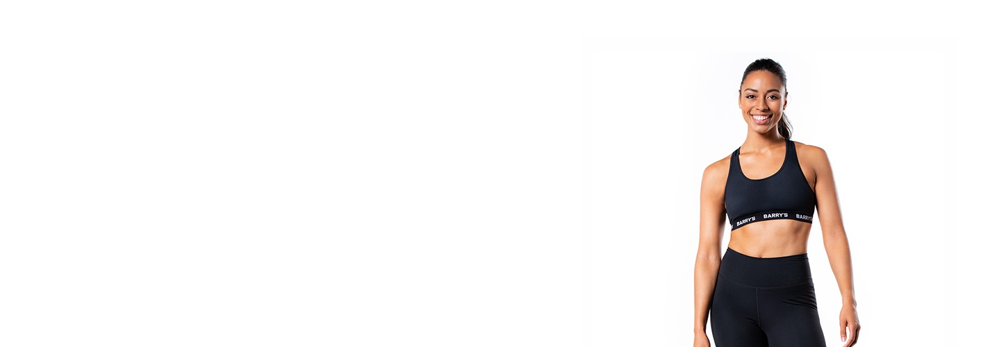 Barry's Bootcamp instructor Mercedes Owens wearing a black sports bra against a white background.