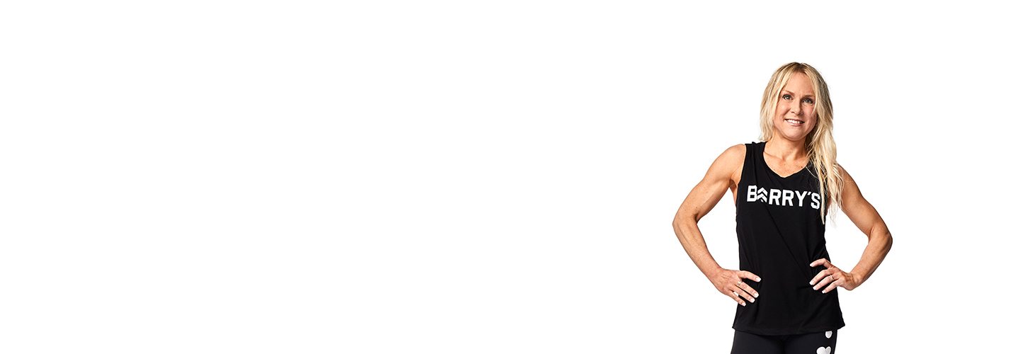 Instructor Rhonda Hunt in black Barry's Bootcamp tank top smiling with hands on hips on white background