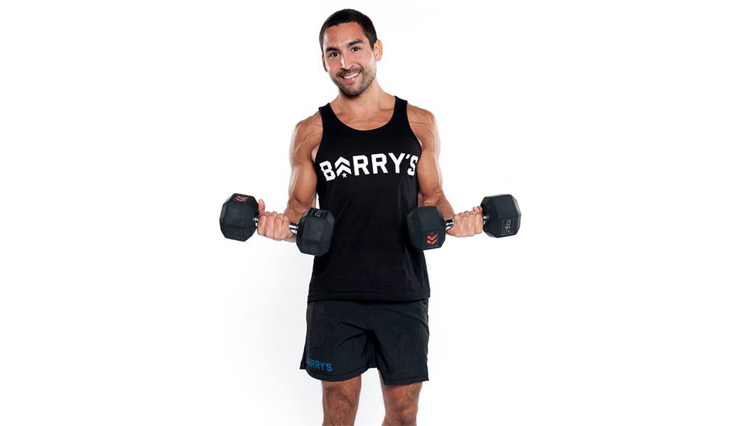 Barry's Instructor Vince Zager wearing black Barry's tank posing with dumbbells
