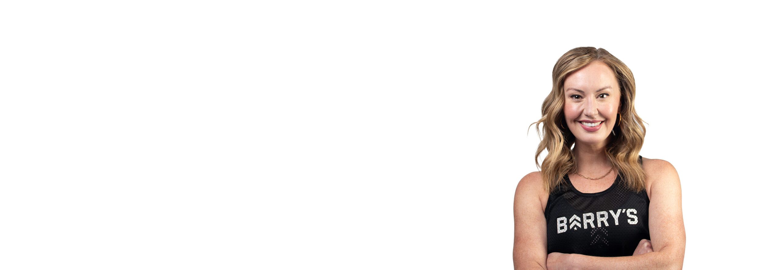 Barry’s instructor wearing a black top standing confidently smiling against a white background