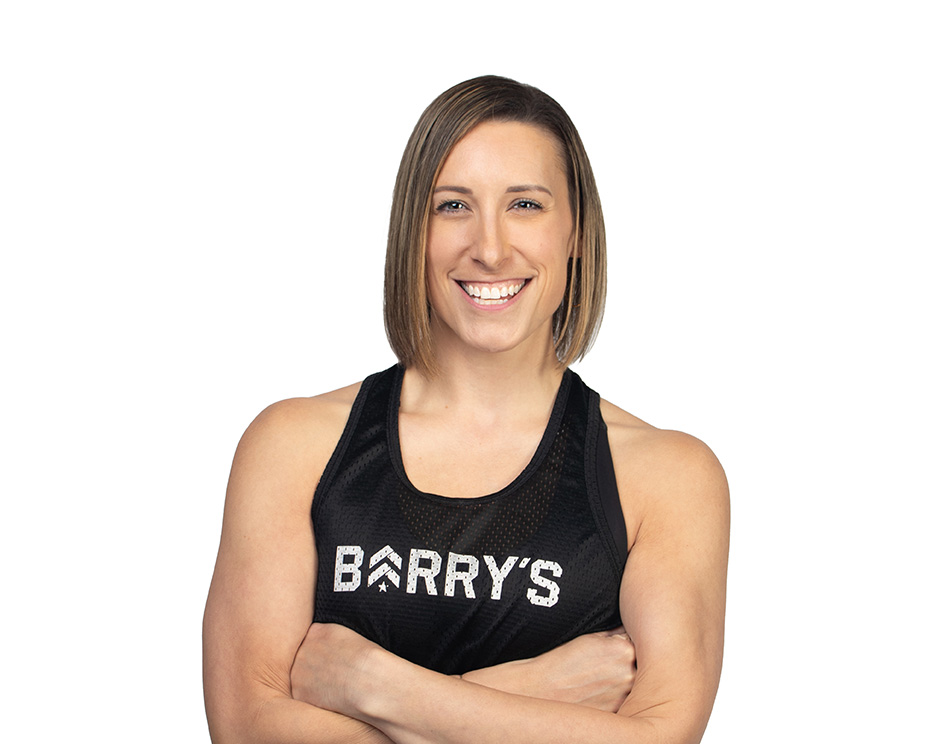 Barry’s instructor wearing a black top standing confidently smiling against a white background