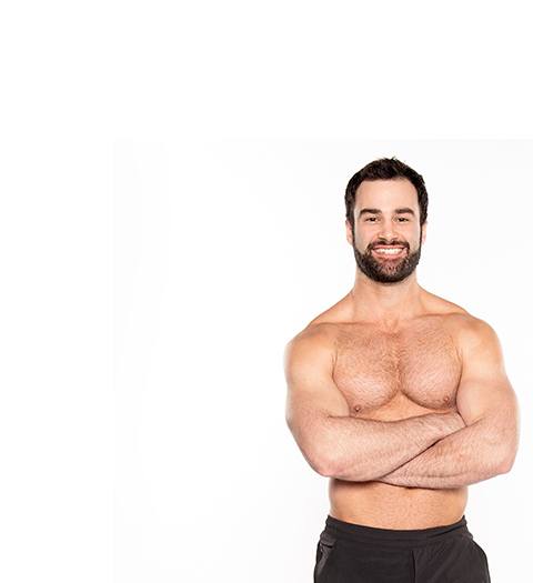Barry's Bootcamp instructor Ben Zerbst shirtless with arms crossed against white background.