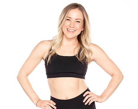 Headshot of Barry's Bootcamp instructor Carly Erickson wearing a black sports bra with her hands on her hips against a white background.
