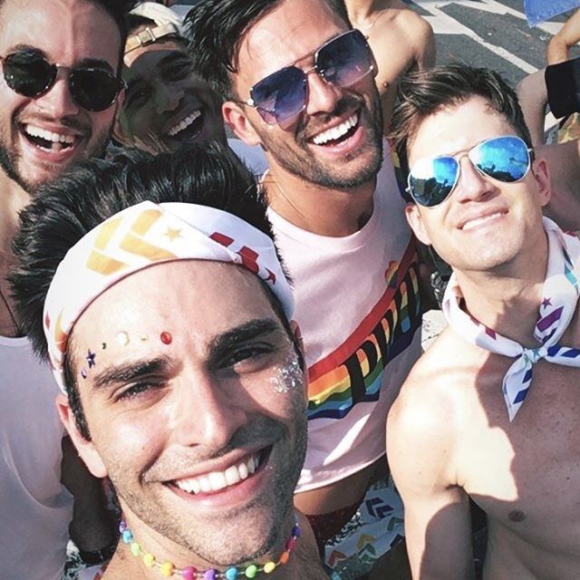 Group of young men wearing rainbow Barry's Bootcamp bandanas and smiling in the sun on the street