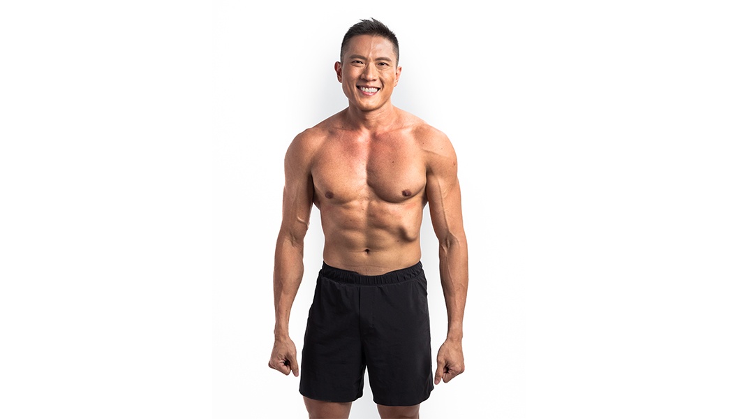 Shirtless Barry's Bootcamp instructor Ian Chan smiling in front of white background