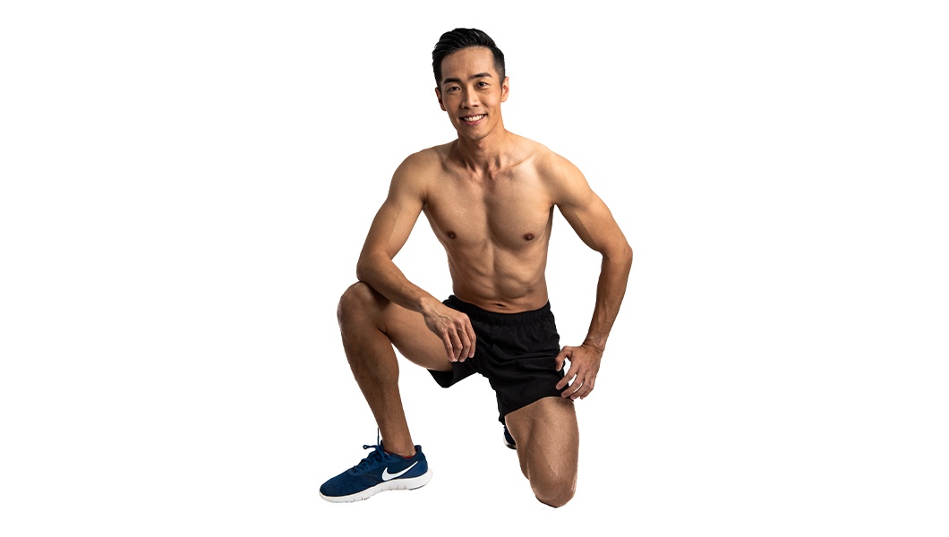 Shirtless Barry's Bootcamp instructor Jeremy Lee on one knee smiling in front of white background
