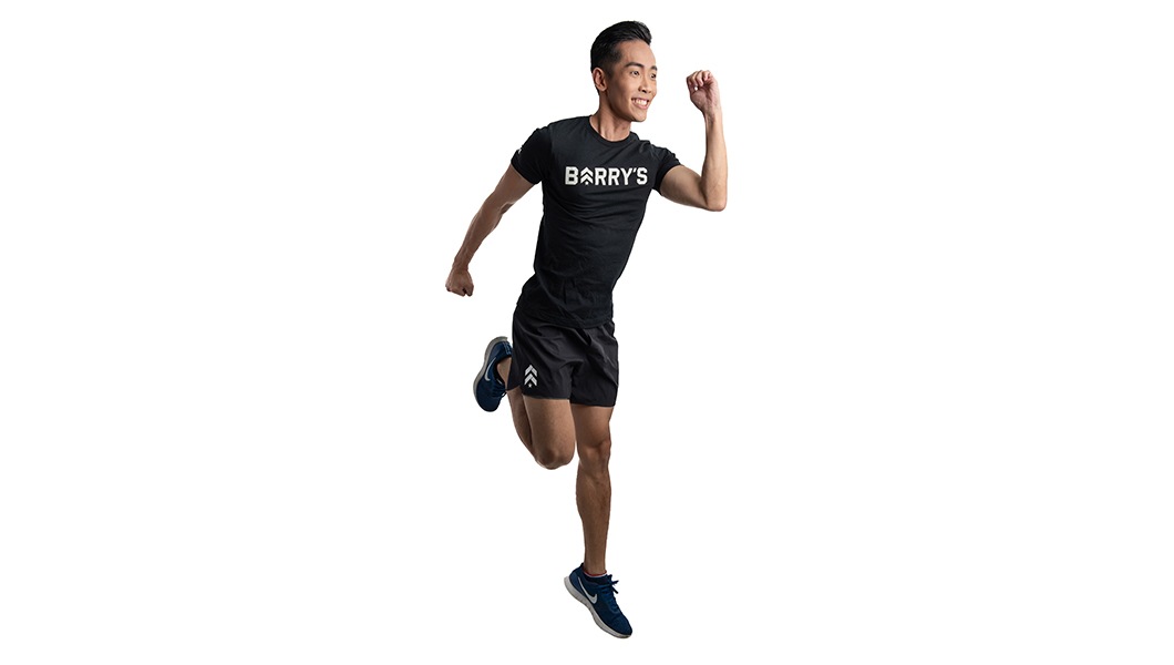 Instructor Jeremy Lee in Barry's Bootcamp t-shirt doing skipping exercise on white background