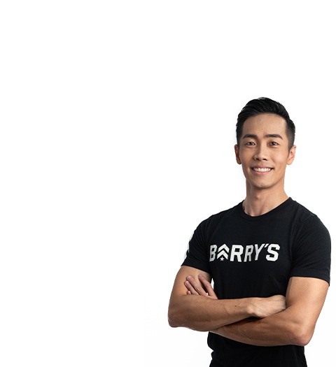 Instructor Jeremy Lee on white background smiling with crossed arms while wearing Barry's Bootcamp t-shirt