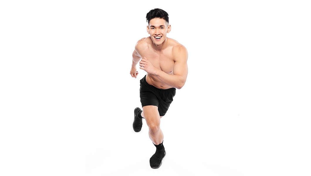 Barry’s instructor shirtless in a runners position smiling against a white background