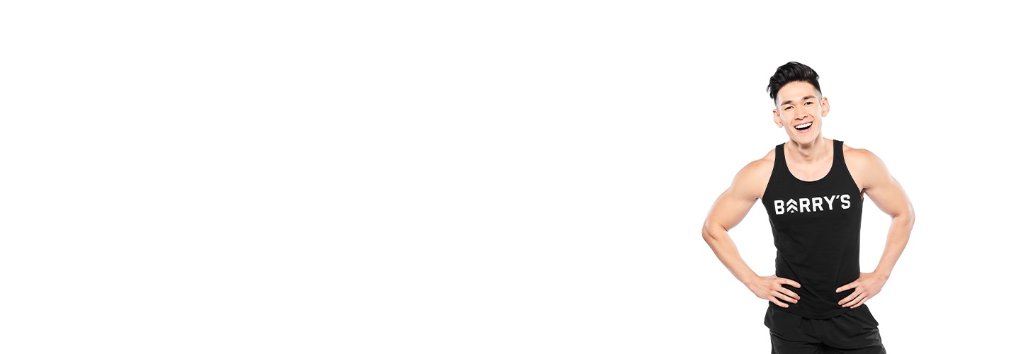 Barry’s instructor wearing a black top standing confidently smiling against a white background