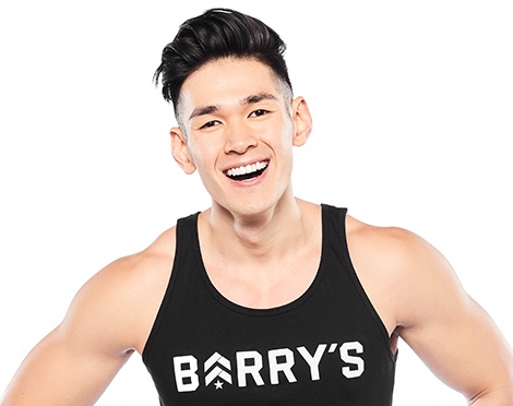 Barry’s instructor wearing a black top standing confidently smiling against a white background
