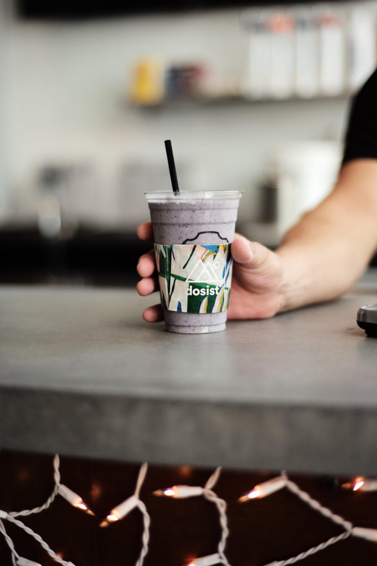 Purple dosist drink on bar counter with twinkle lights hanging underneath