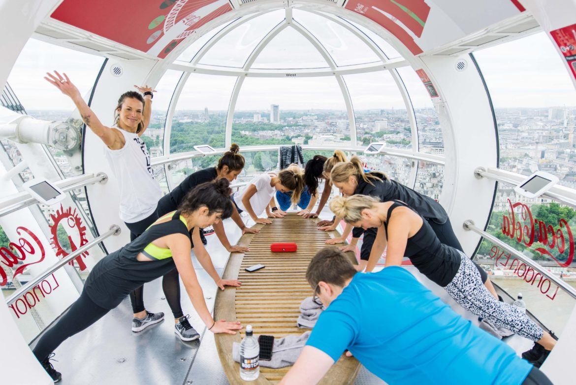 Barrys Bootcamp-instruktör ser stolt ut när en liten grupp gör armhävningar i en London Eye-pod