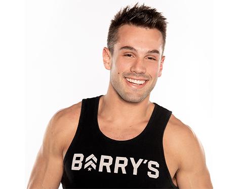 Barry's Bootcamp instructor Nick Tipple wearing a black Barry's tank top and smiling against a white background.