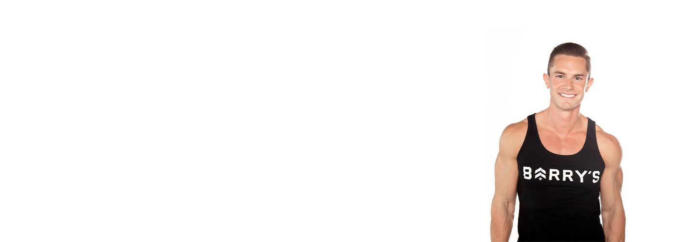 El instructor de Barry se mantiene firme, vistiendo una camiseta sin mangas negra sobre un fondo blanco, listo para el próximo desafío de entrenamiento.
