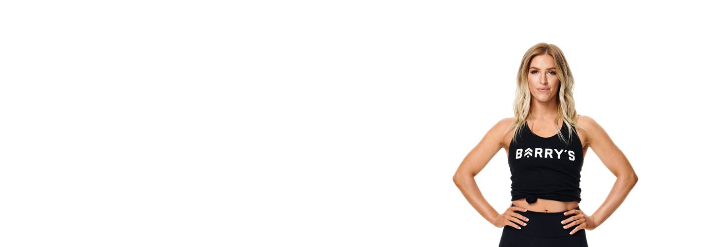 Instruktör Nicole Christey i Barry's Bootcamp linne med målmedvetet ansikte och båda händerna på höfterna