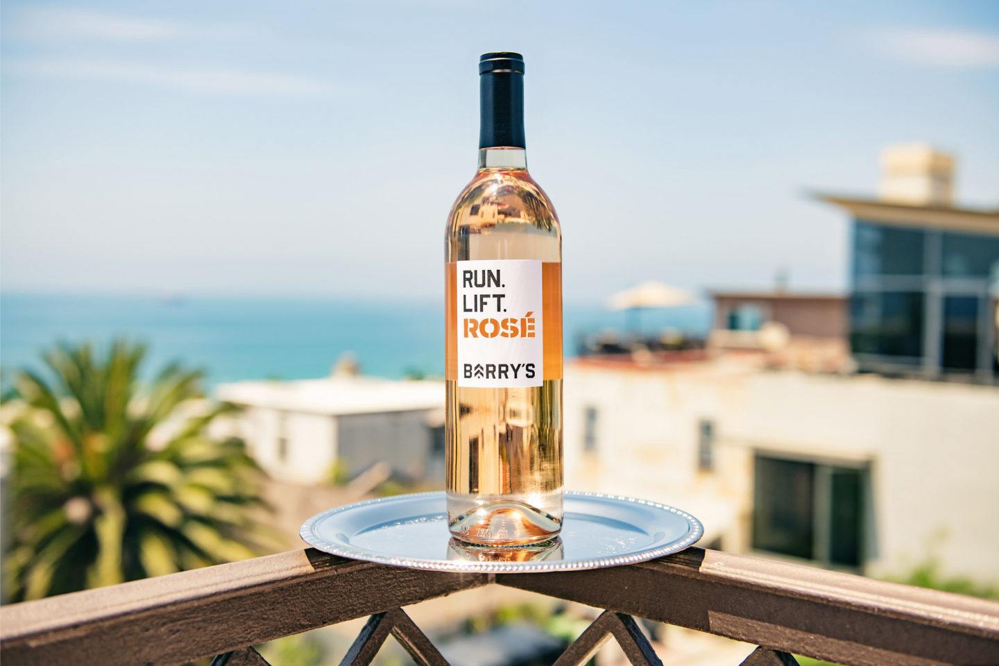 Singular Run Lift Rosé bottle on silver dish with beach and palm trees in the background