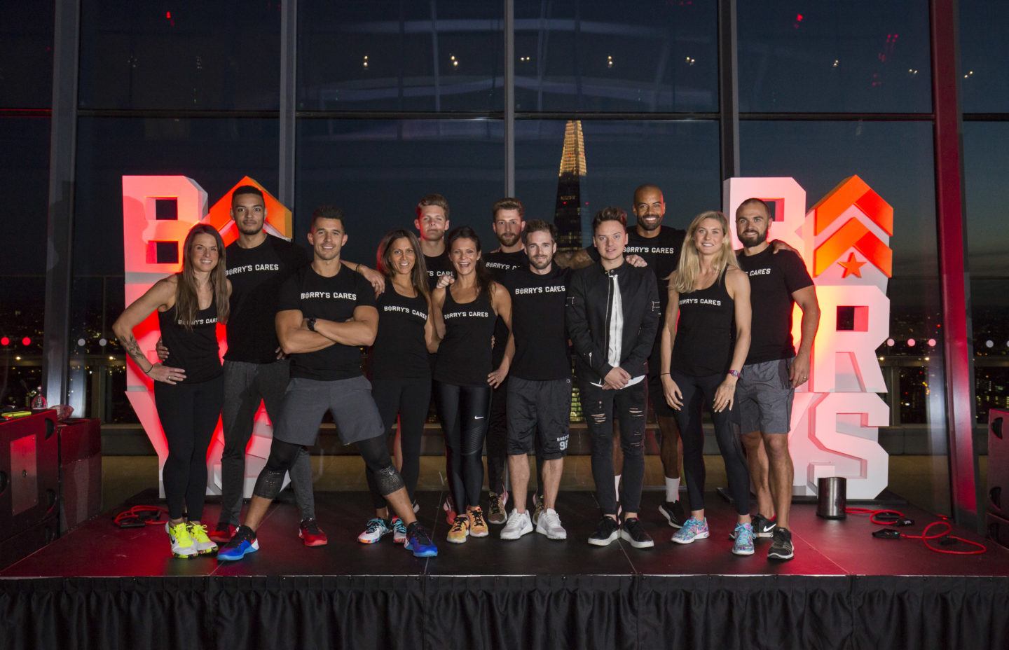 London Sky Garden selv instruktører, der står sammen foran Barry's Bootcamp-logoer iført Barry's Cares-t-shirts