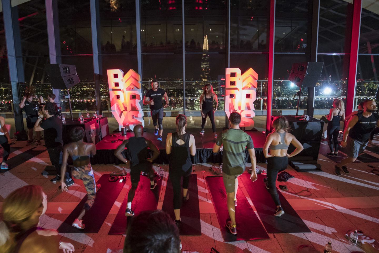 المشاركون في Barry's Bootcamp London Sky Garden يتبعون المدربين الذين يقومون بحركات اللياقة البدنية على المسرح