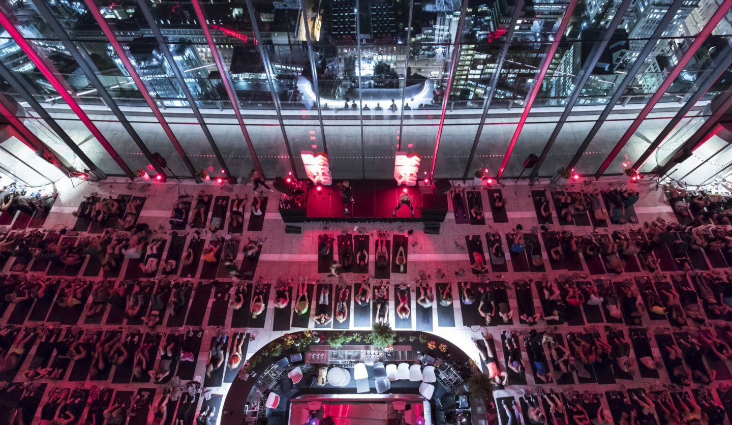 Overhead view of Barry's Bootcamp class at the London Sky Garden in front of red lights and large glass windows