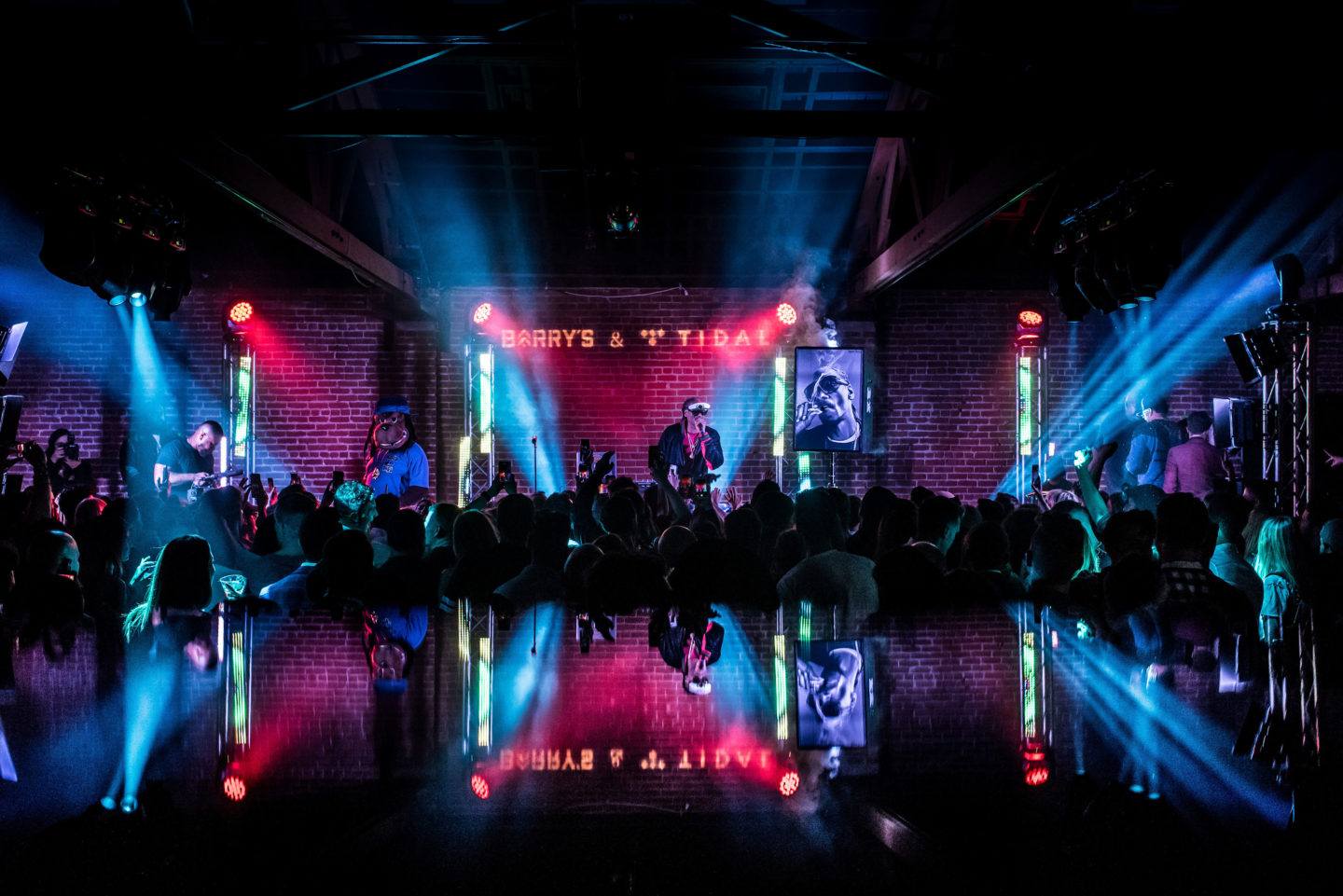 Performer at Barry's Bootcamp decades party on dark stage with blue and red lights