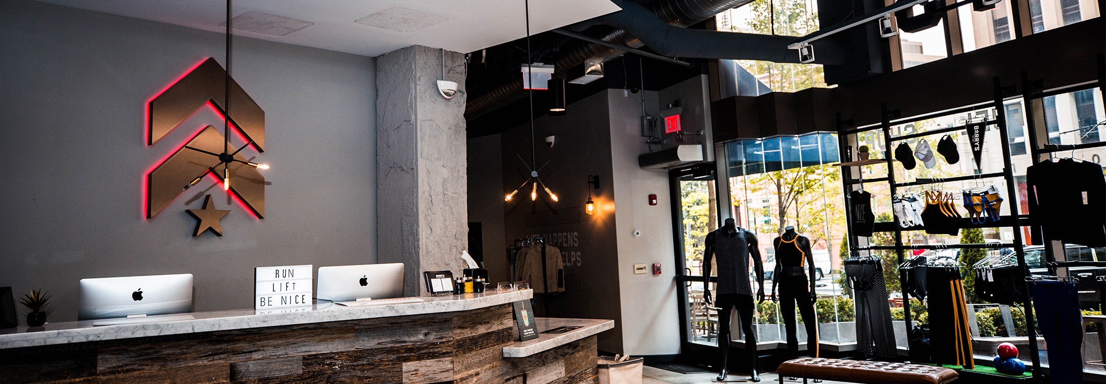 Gold Barry's Bootcamp upward arrows and star logo with red backlighting on wall behind reception desk at Washington D.C. studio location